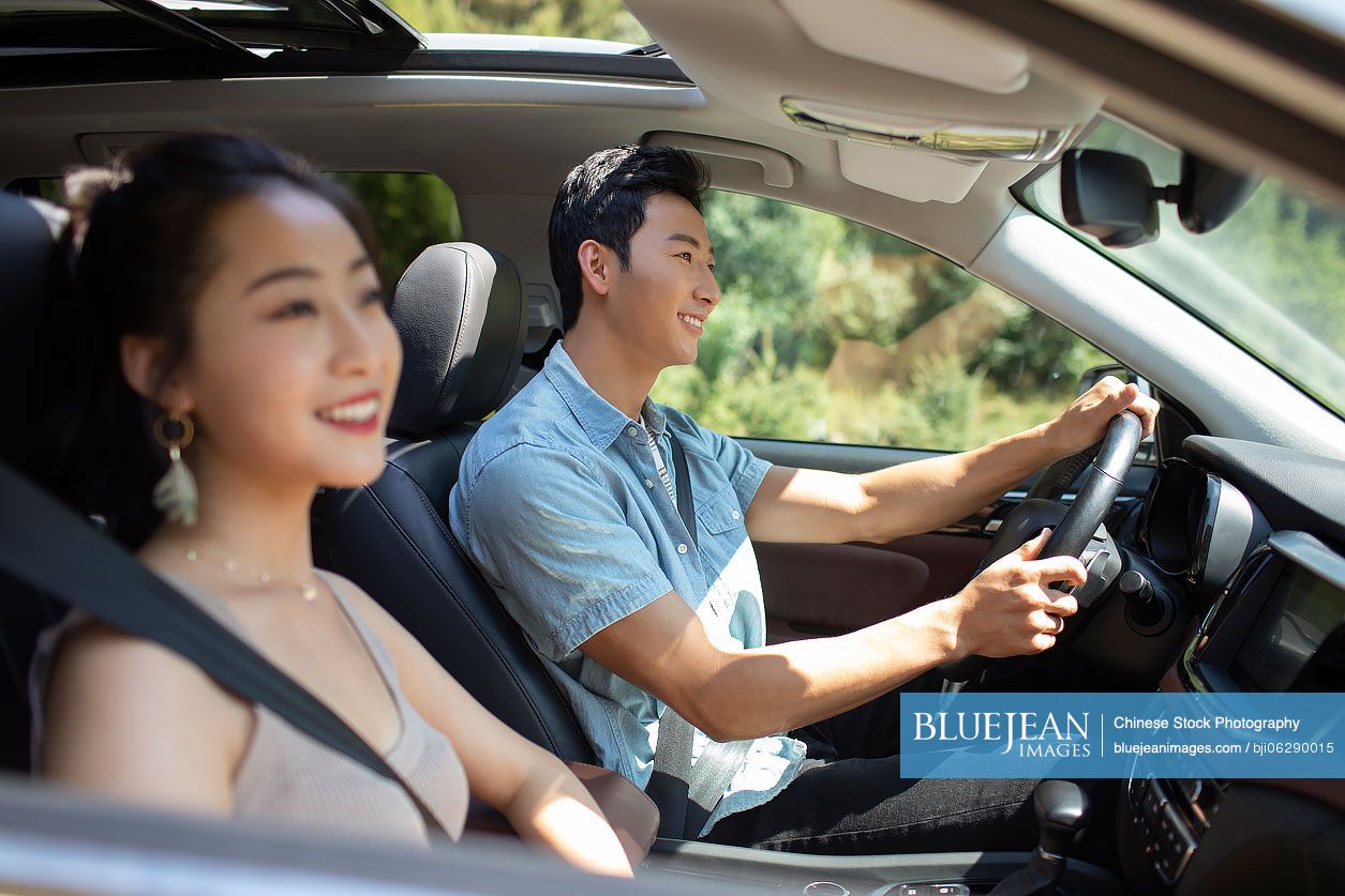 Happy young Chinese couple enjoying road trip
