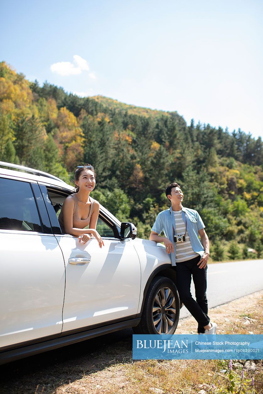 Happy young Chinese couple enjoying road trip