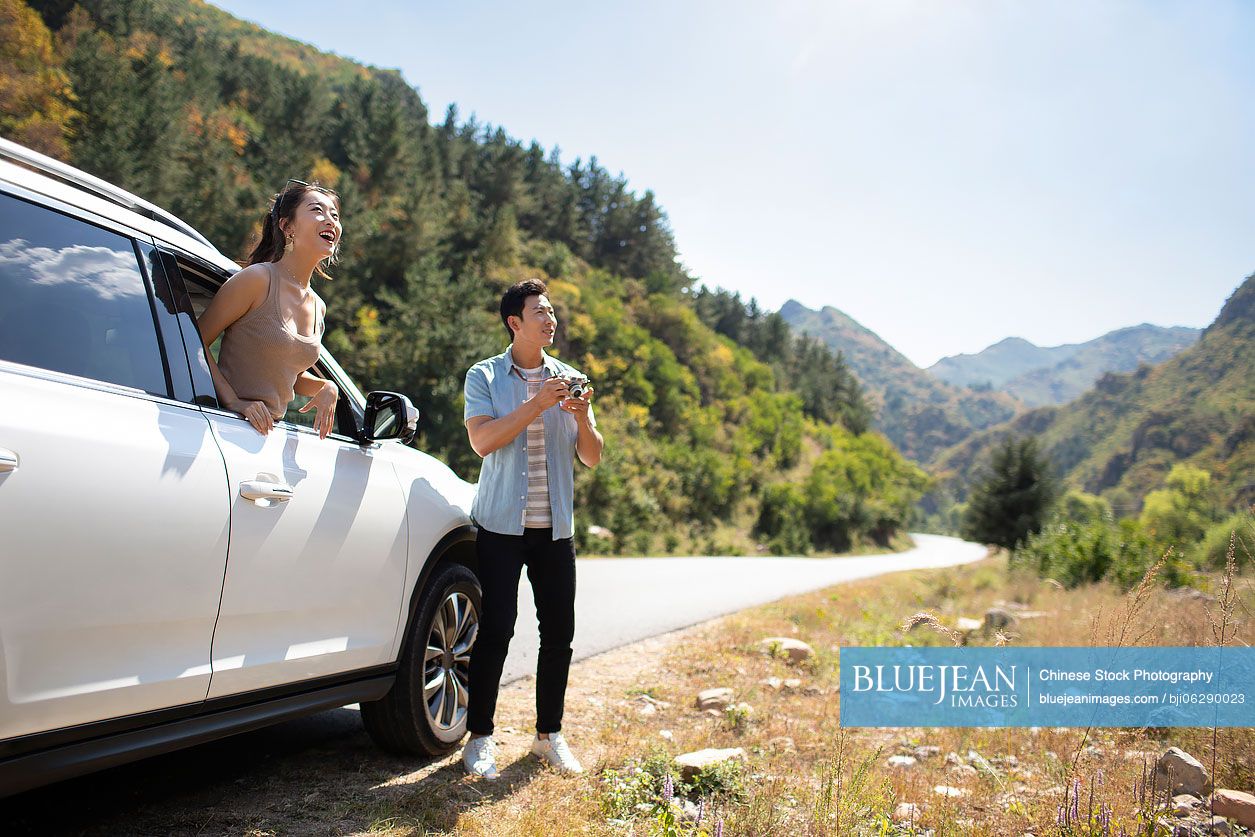 Happy young Chinese couple enjoying road trip