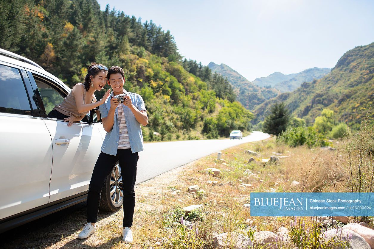 Happy young Chinese couple enjoying road trip