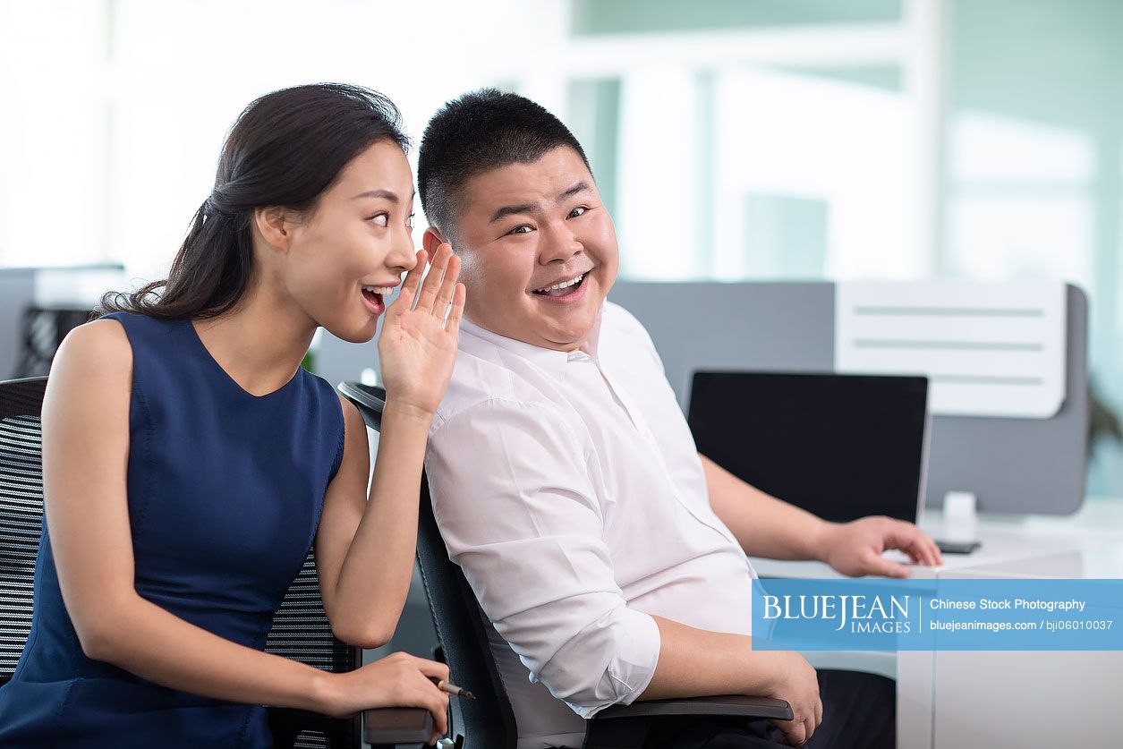 Chinese business people talking gossip in office