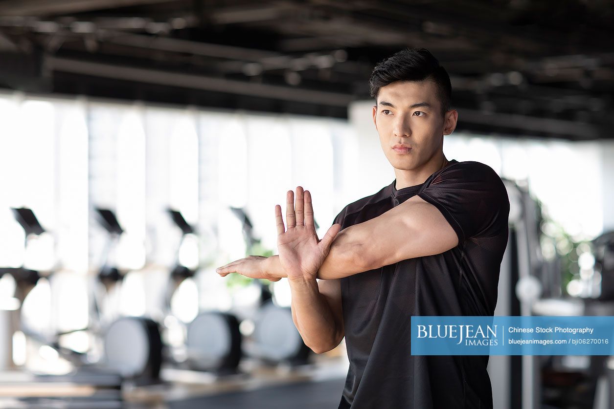 Young Chinese man stretching at gym