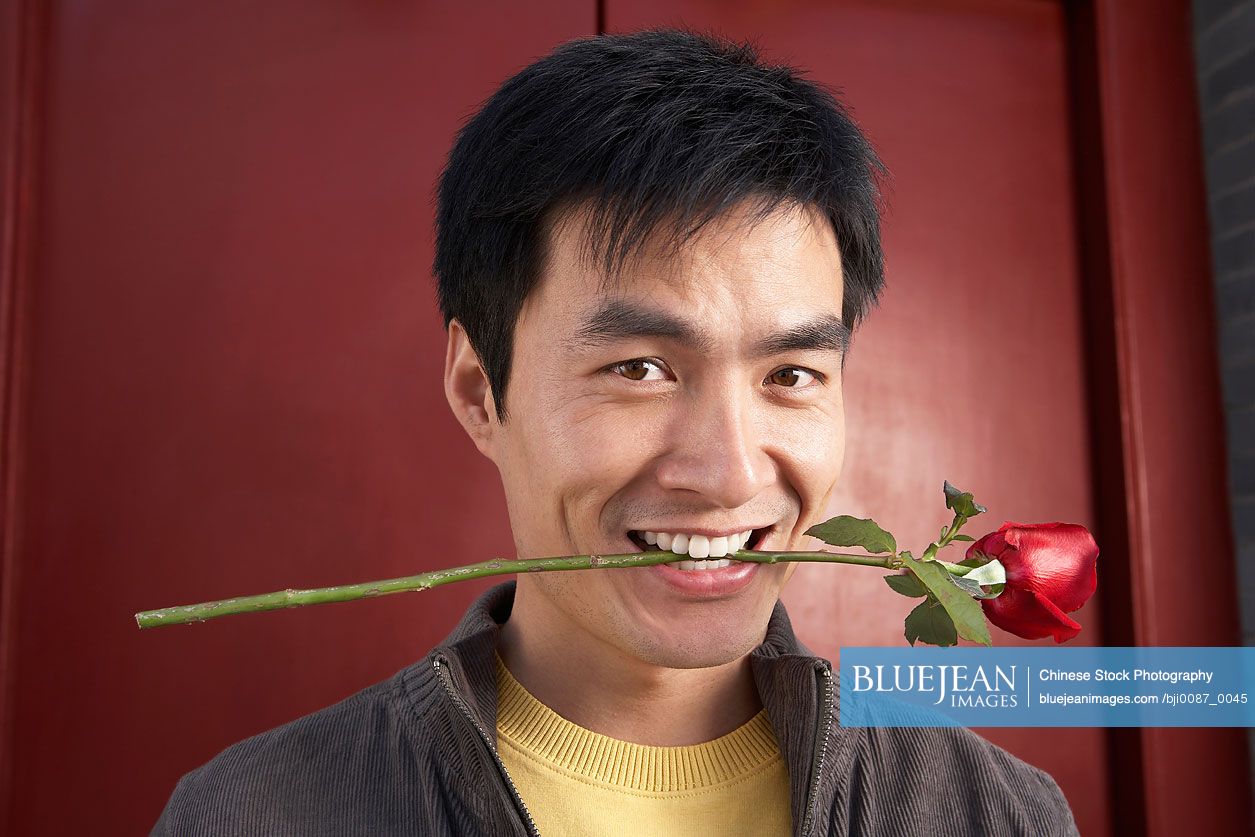 Chinese Young Man Waiting Outside Front Door Holding A Rose In His Mouth
