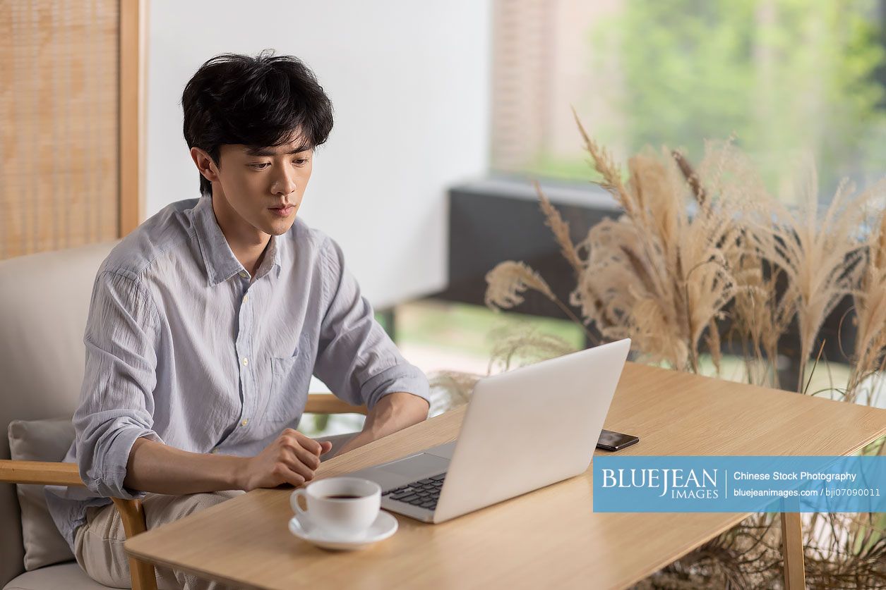 Young Chinese man using laptop in café-High-res stock photo for download