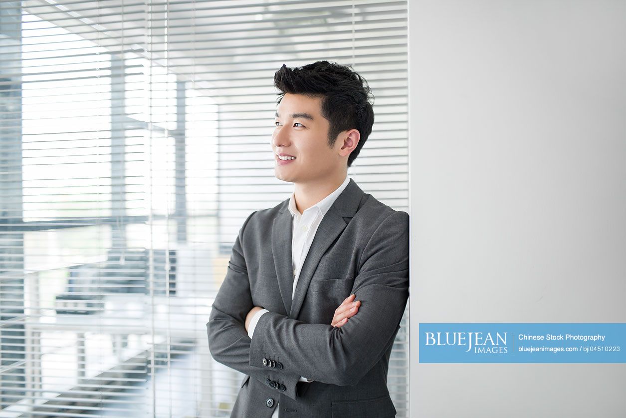 Young Chinese businessman thinking in office