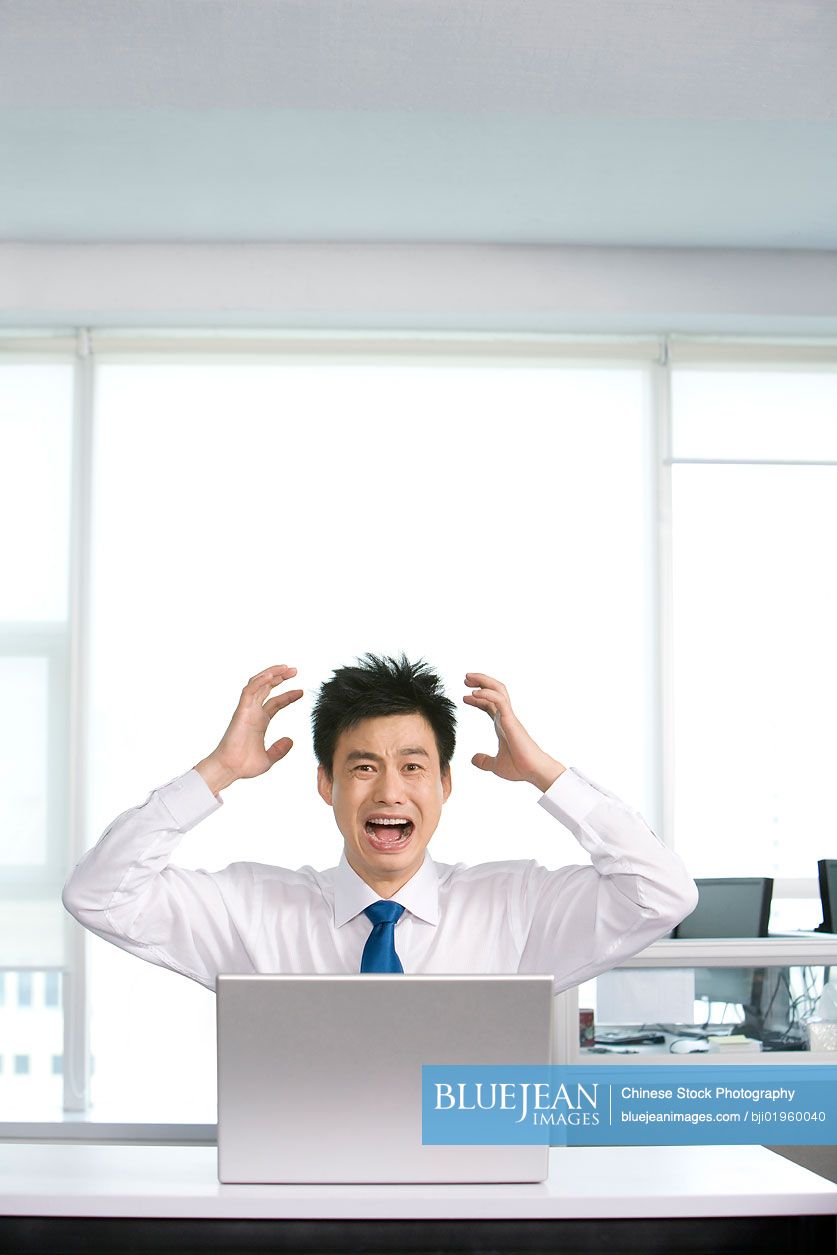 Frustrated Chinese office worker at his desk
