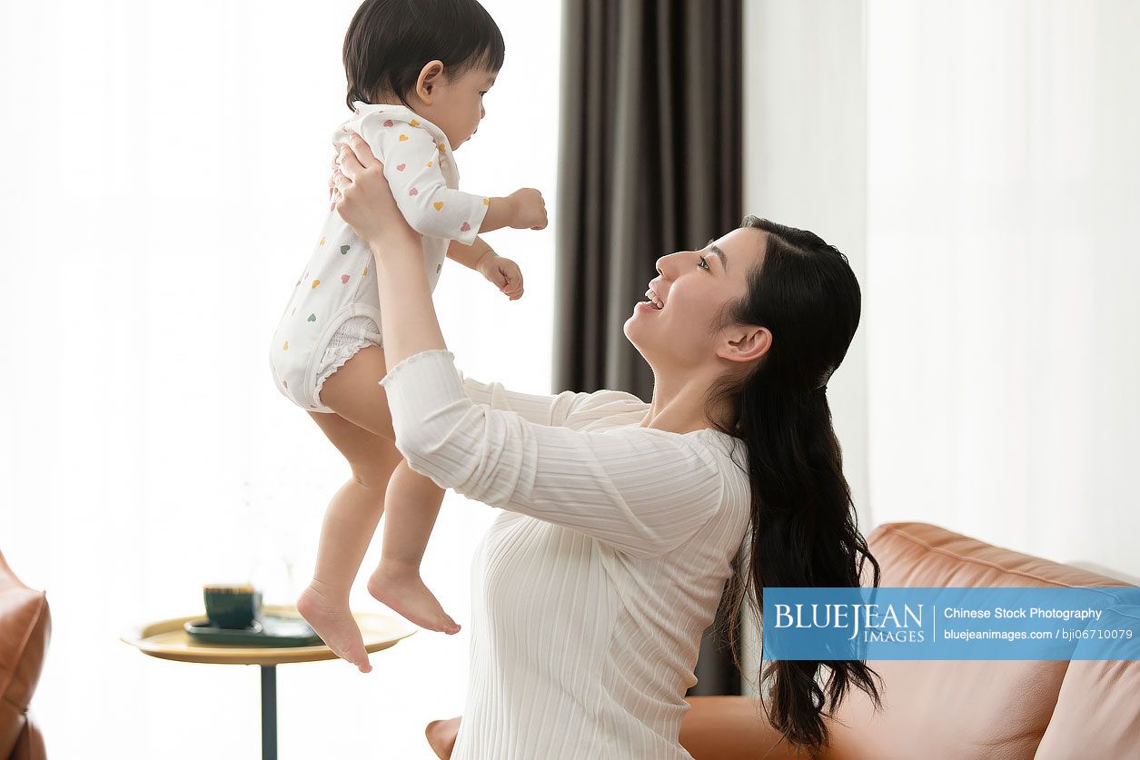 Happy young Chinese mother taking care of her baby