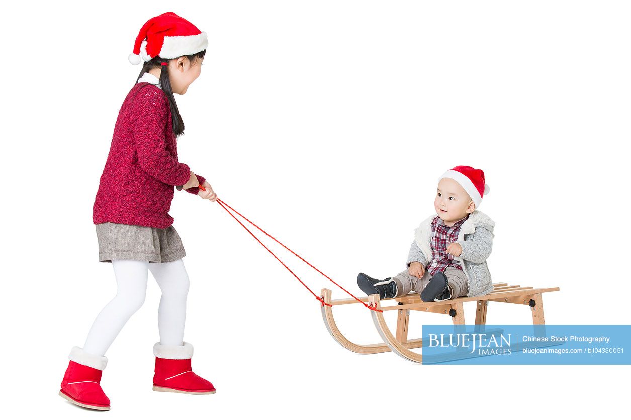 Chinese sister and brother playing with sled