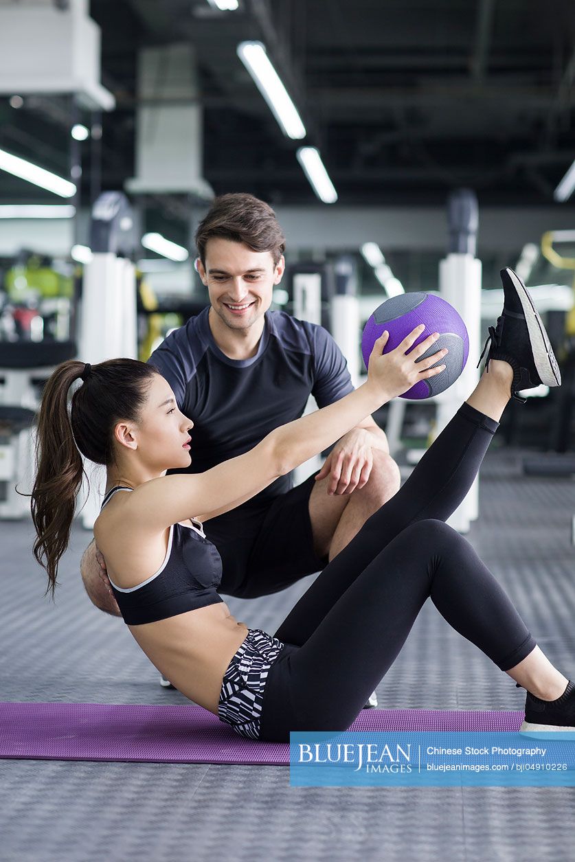 Young Chinese woman working with trainer at gym