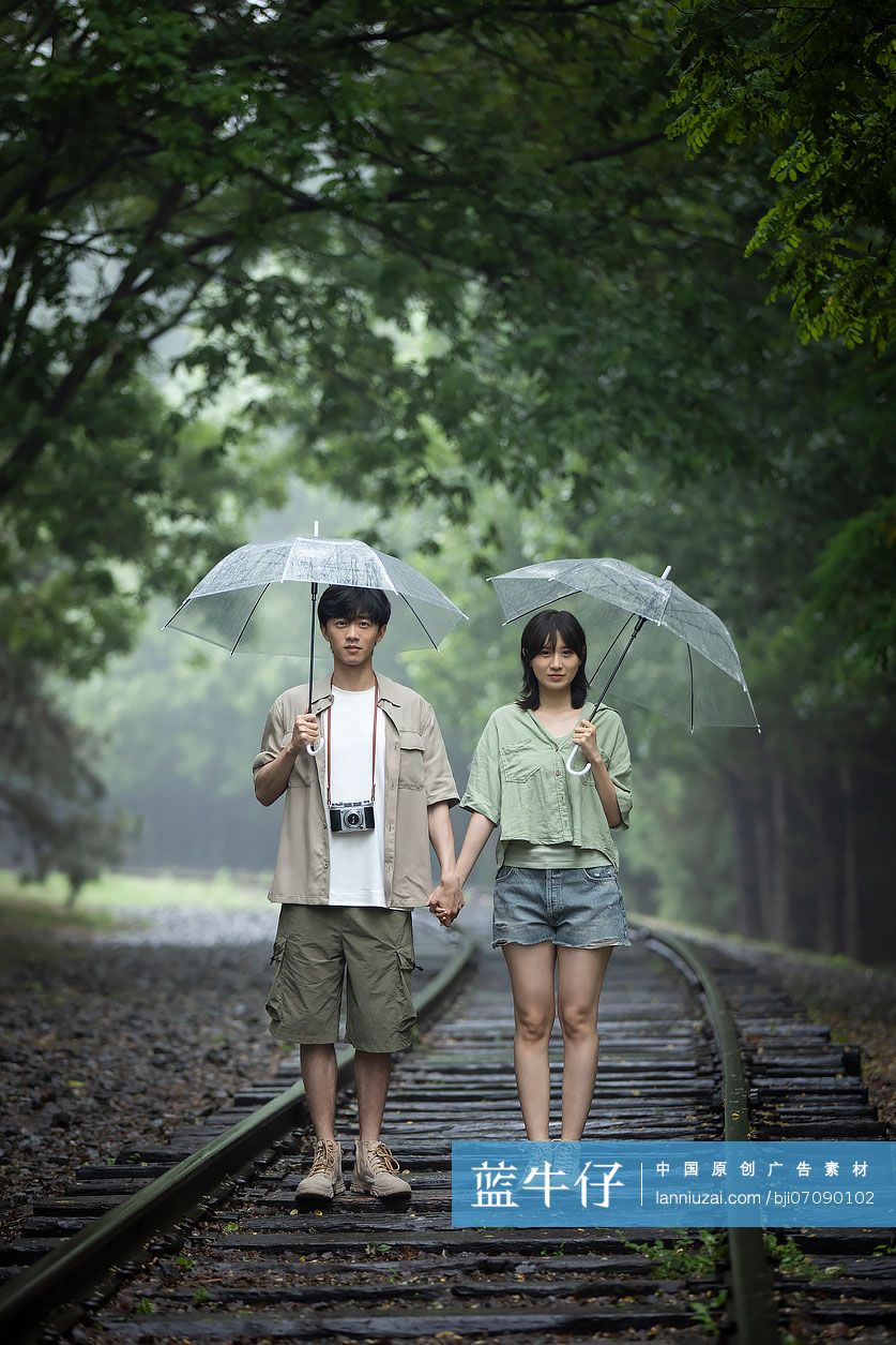 年轻情侣打着伞雨中散步