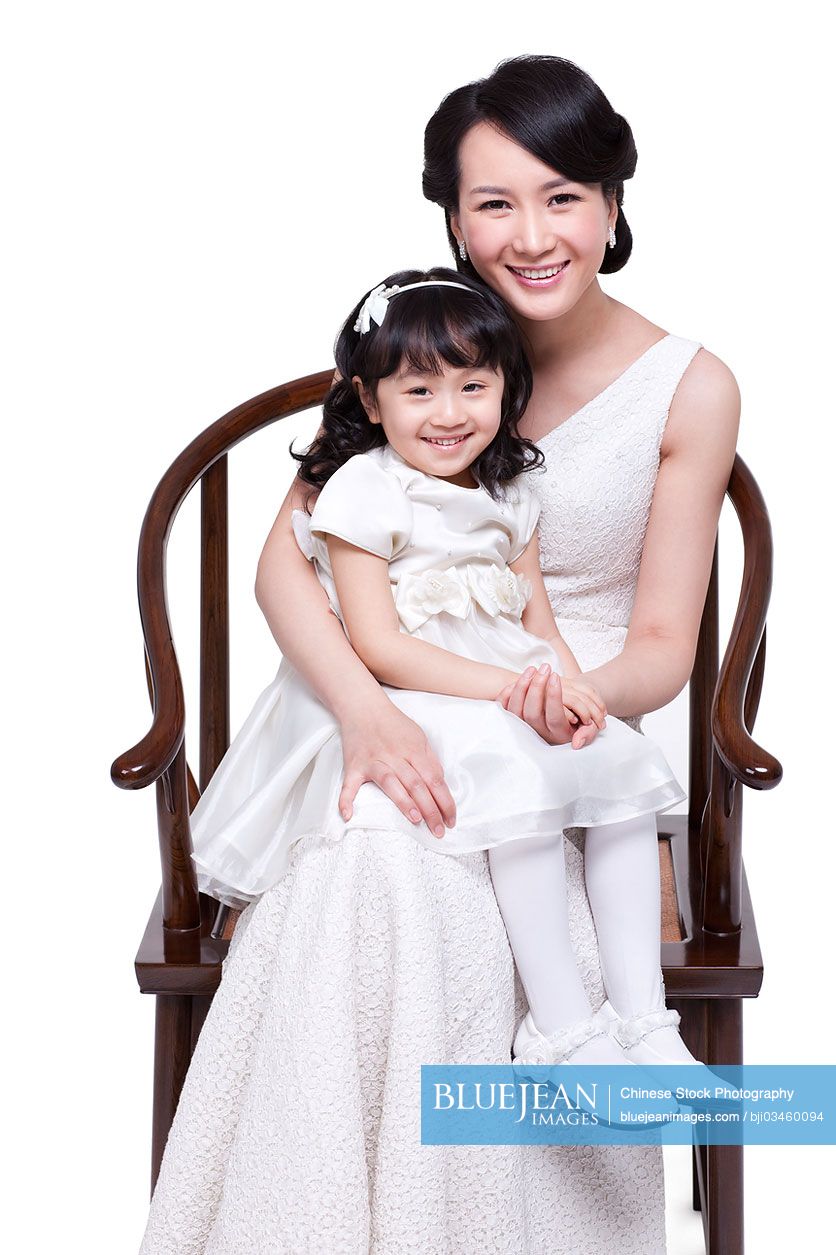 Happy Chinese mother with little daughter sitting on lap
