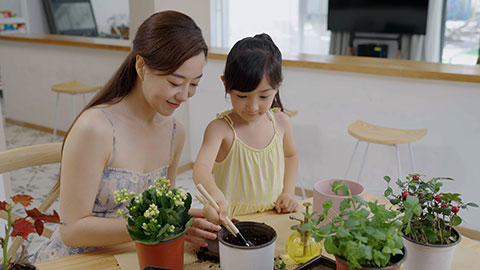 Mum and daughter enjoy potting plants together at home