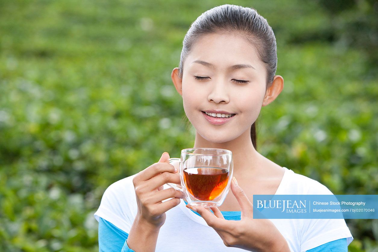 Young Chinese woman drinking tea in a tea field-High-res stock photo ...