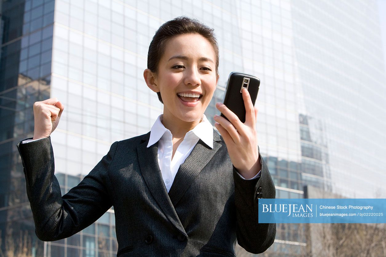 Chinese businesswoman receiving good news on mobile phone