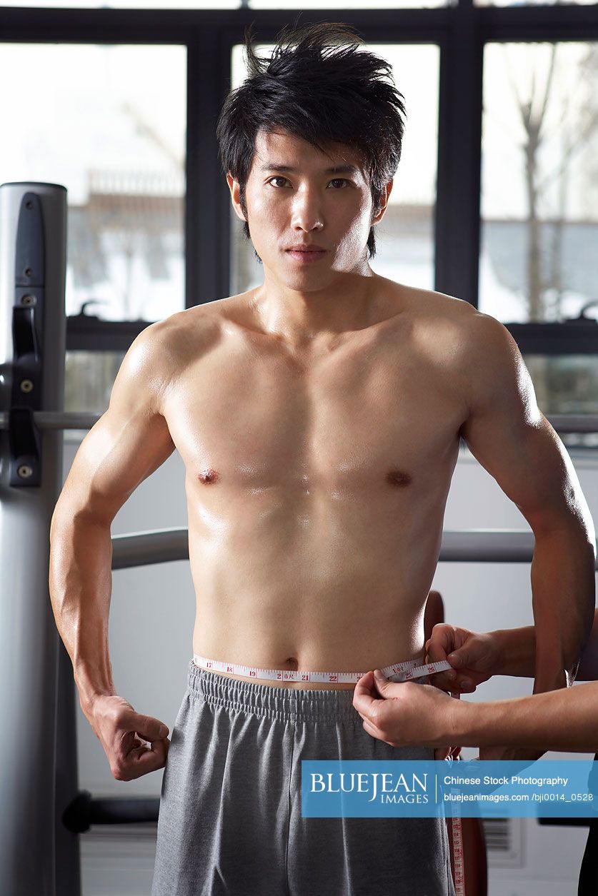 Young Chinese man measuring body at the gym