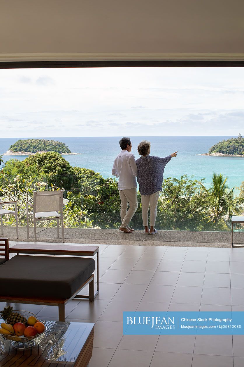 Senior Chinese couple enjoying scenery on balcony