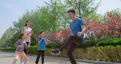 快乐的年轻家庭在公园踢毽子