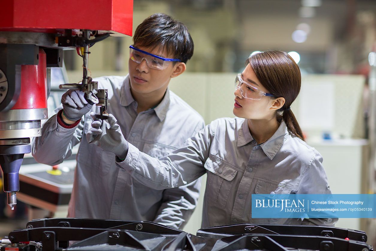 Young Chinese engineers checking machine in the factory