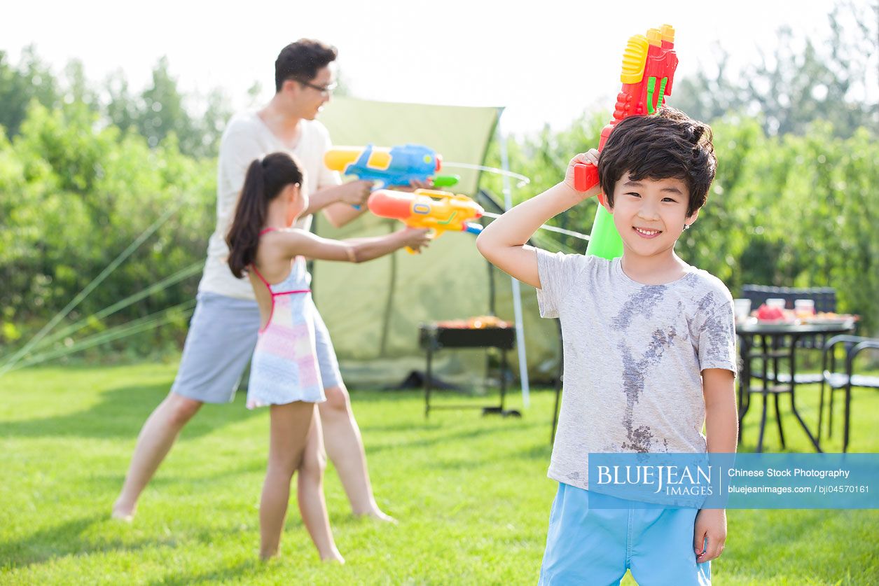 Happy Chinese father and children playing squirt guns