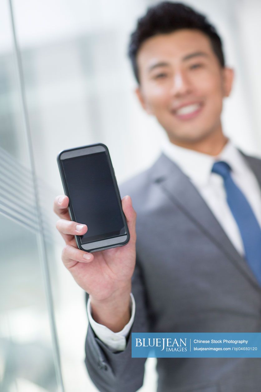Young Chinese businessman showing smart phone
