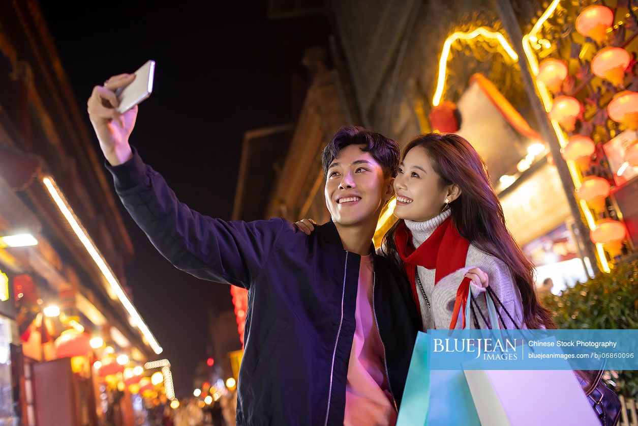 Young Chinese couple taking selfie with smart phone