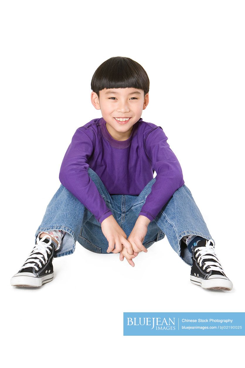 Happy young Chinese boy sitting on the ground