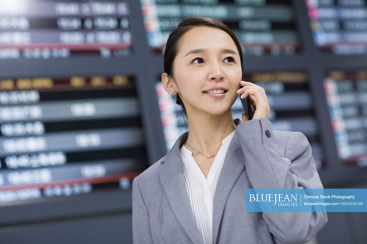 Young Chinese businesswoman talking on phone in airport