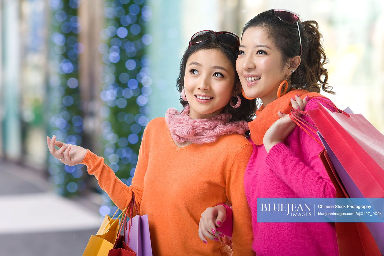 Two young women holding up shopping bags