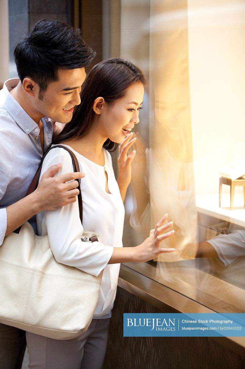 Sweet young Chinese couple doing window shopping in Hong Kong