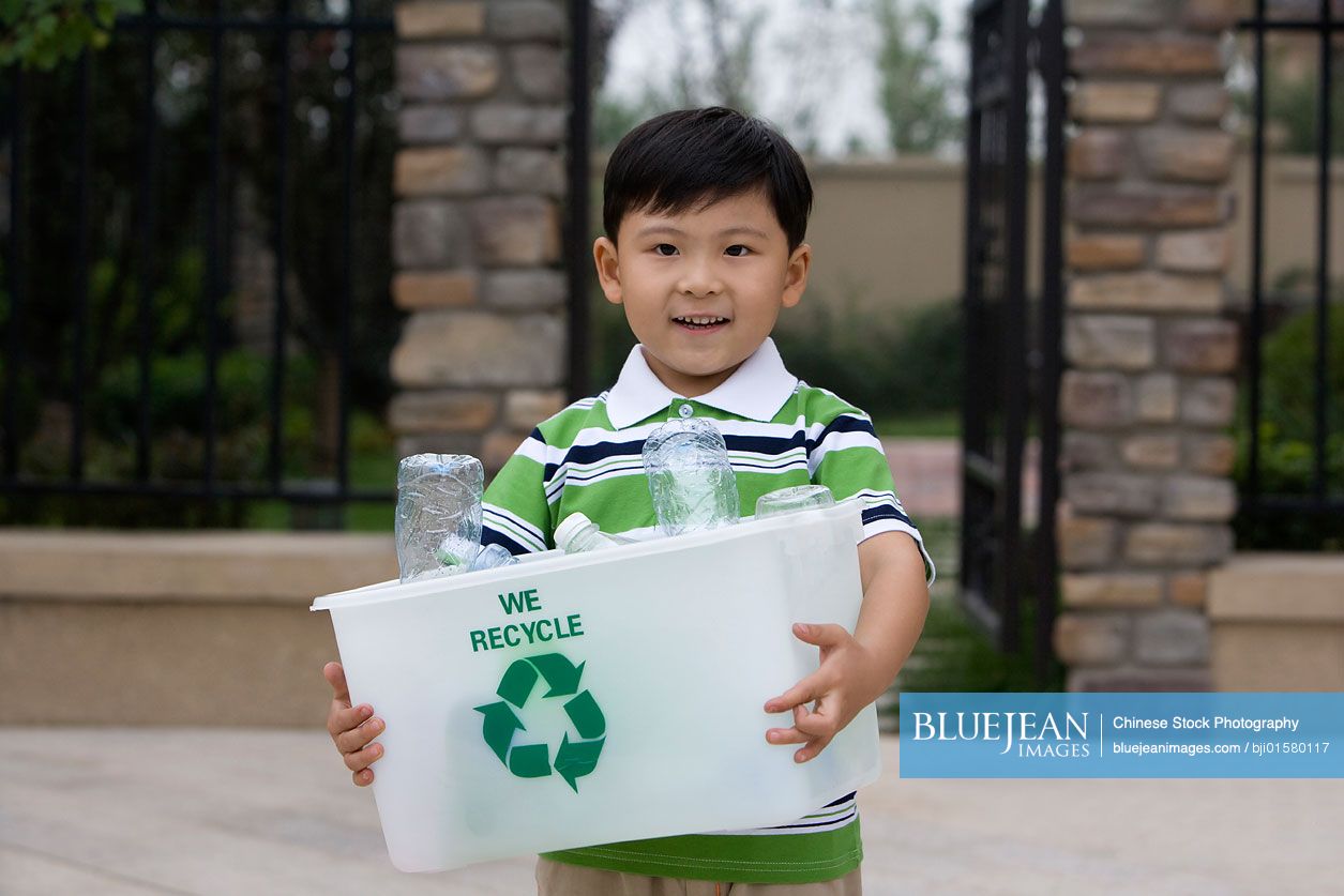 Little Chinese boy holding recycling box