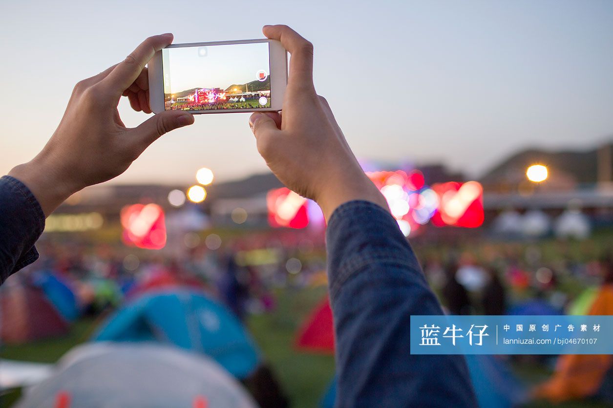 年轻男子在音乐节上用手机拍照