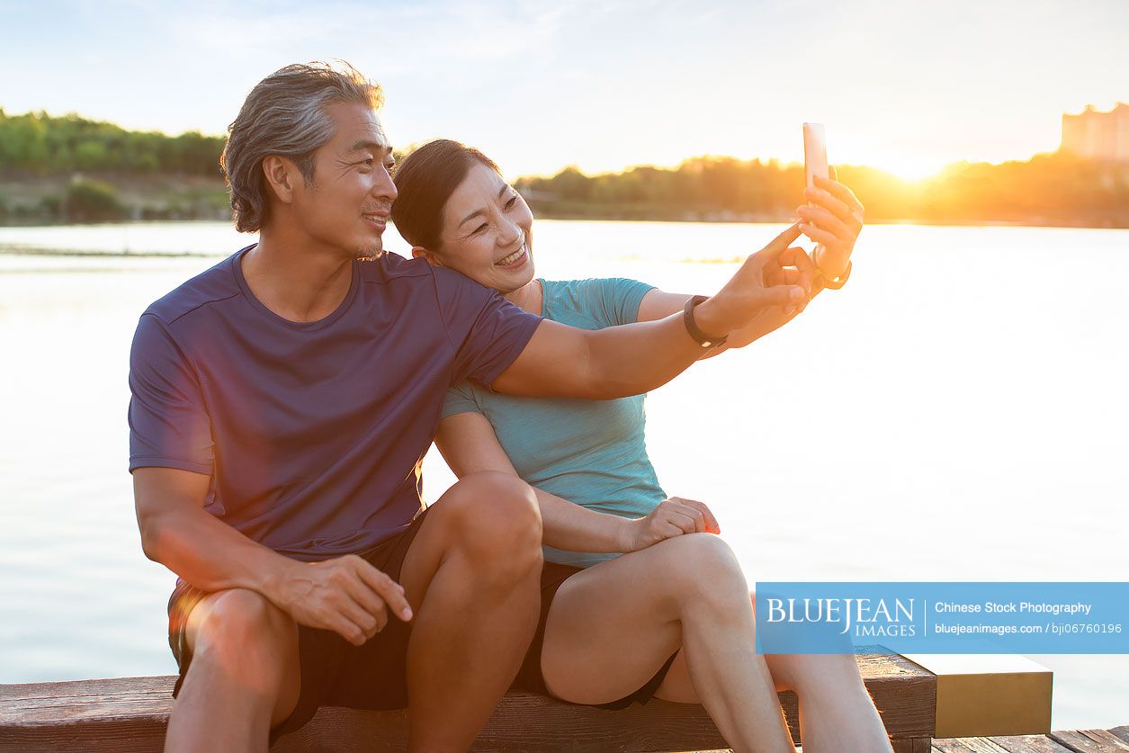 Happy mature Chinese couple taking selfie in park