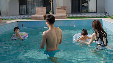 Happy family swimming and playing in the sparkling pool