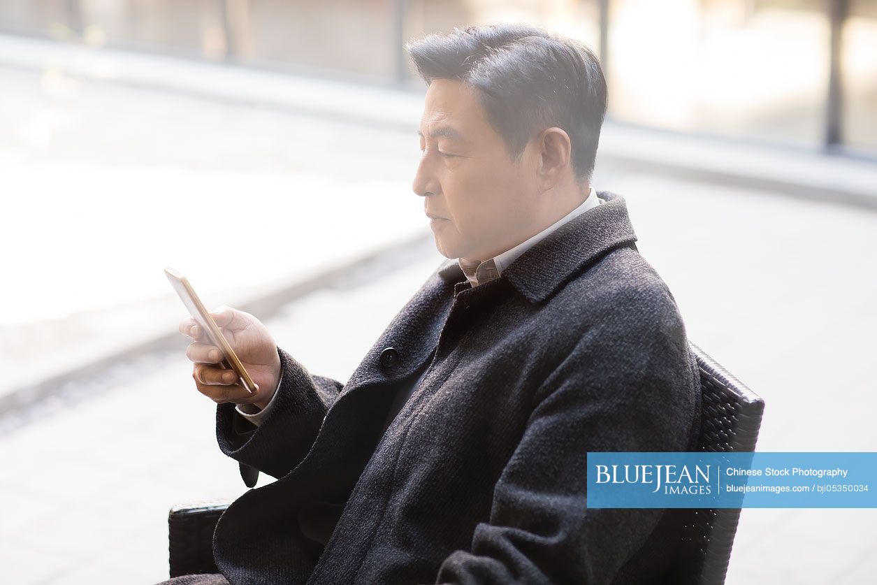 Mature chinese man using smart phone high res stock photo for download