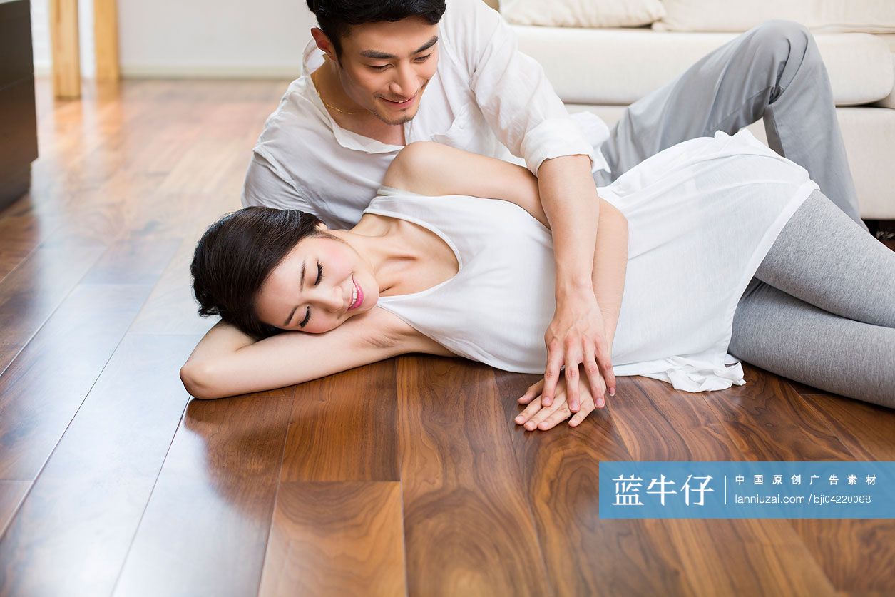 快乐的年轻情侣躺在木地板上