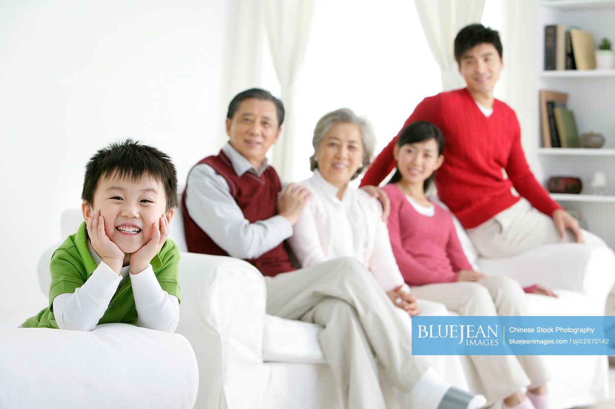 Young Chinese boy in a living room with parents and grandparents in the background