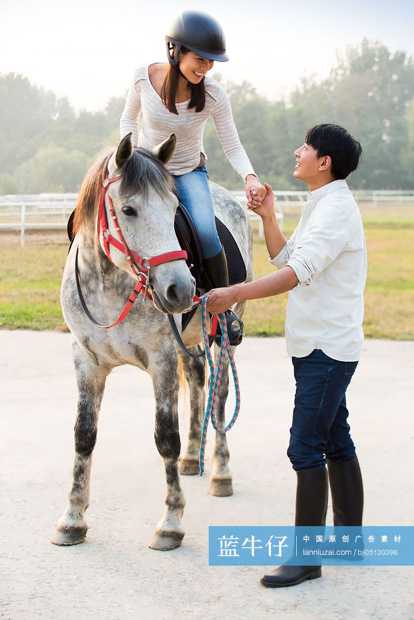 年轻情侣在马场骑马