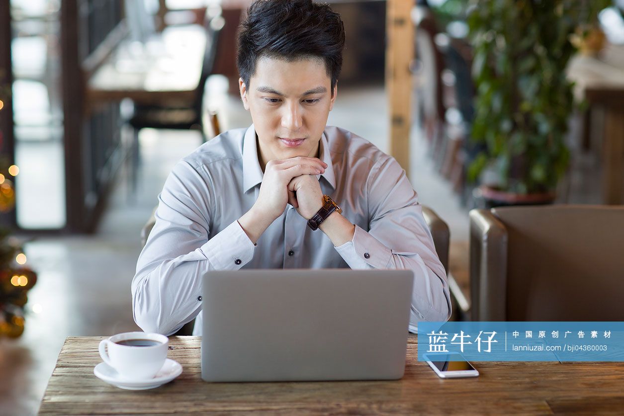 年轻男子在咖啡馆使用笔记本电脑