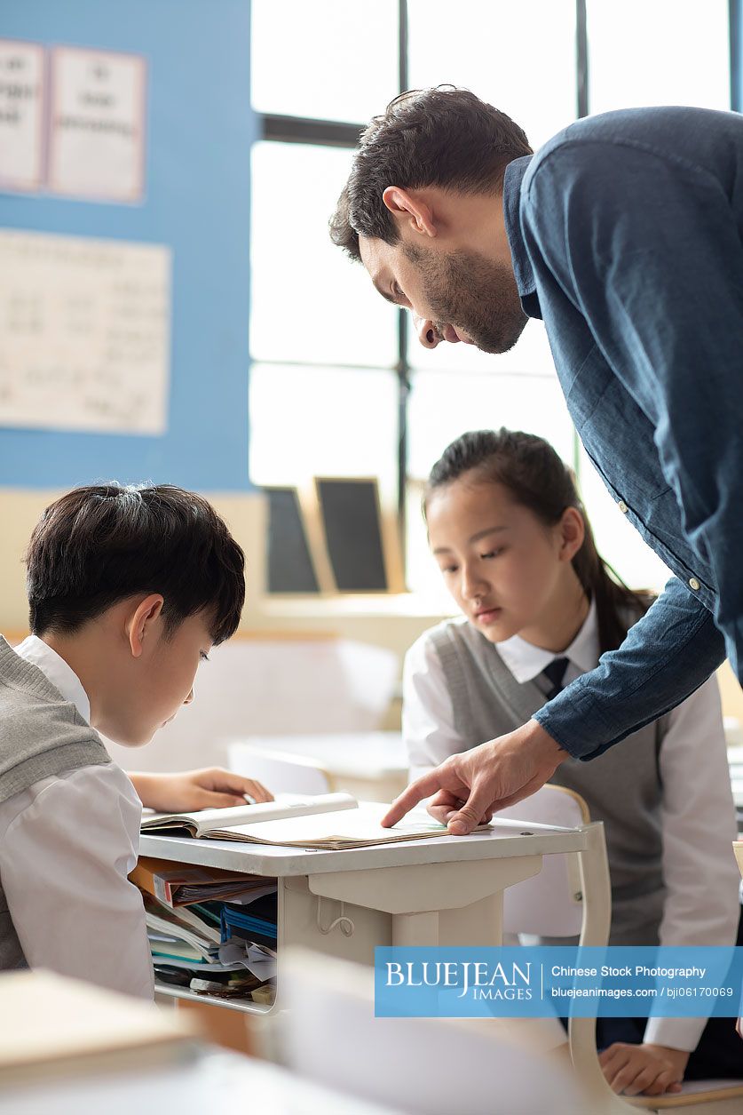 Young teacher helping students in classroom