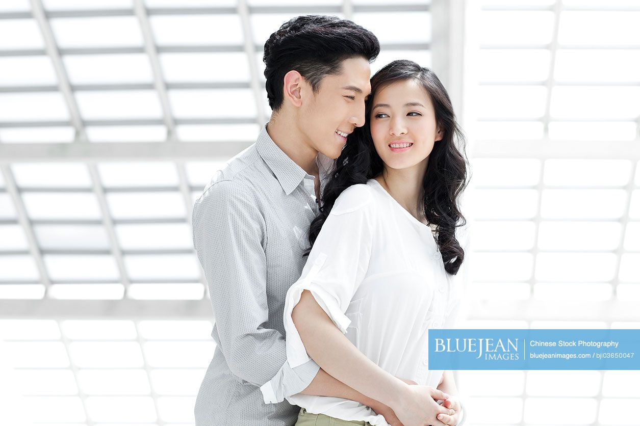 Chinese young couple embracing in airport lobby