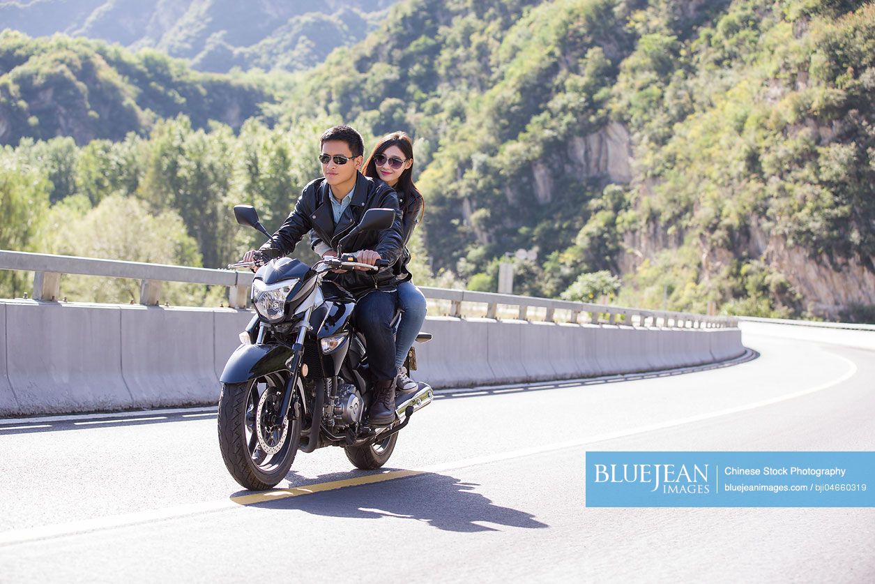 Young Chinese couple riding motorcycle together