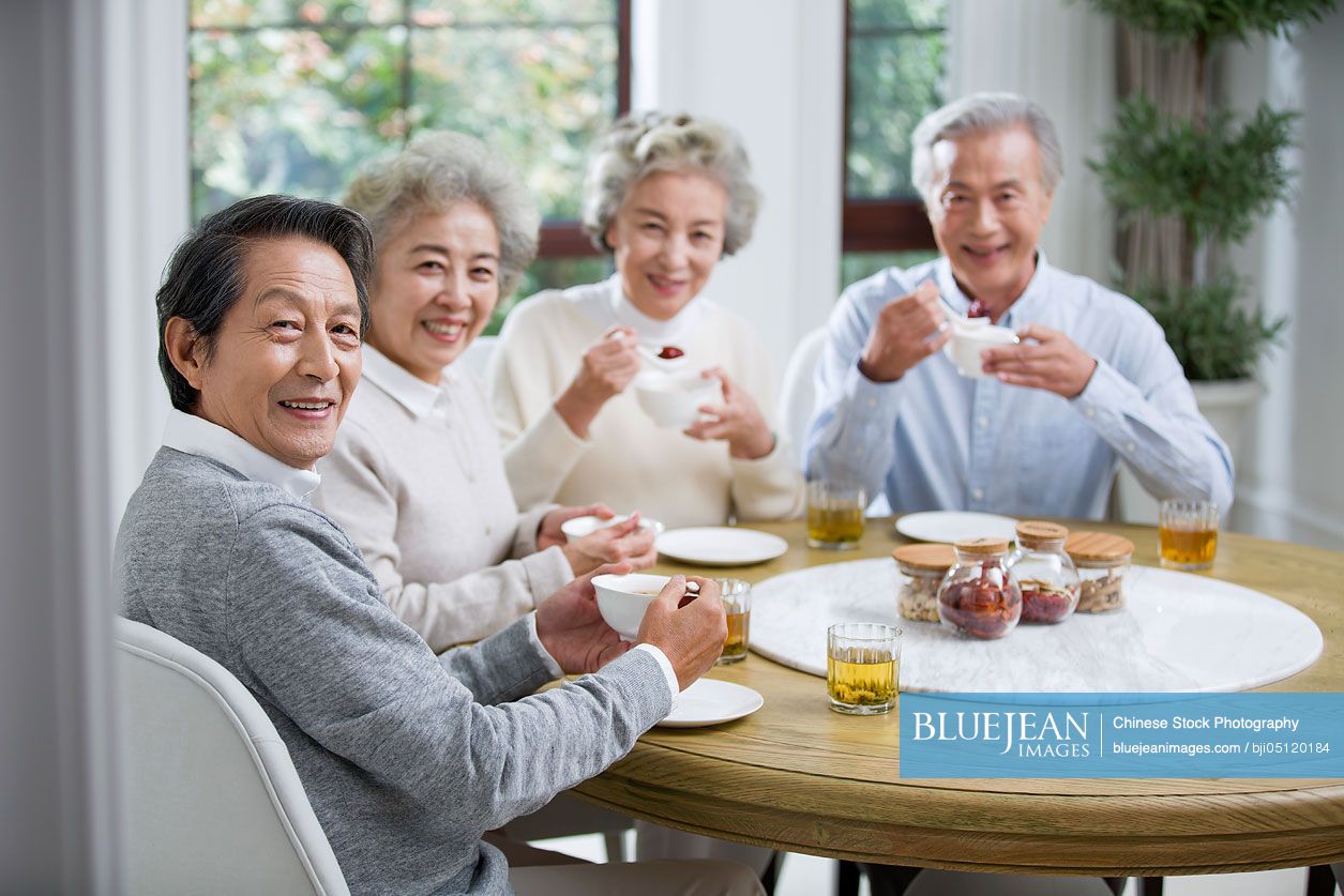 Happy senior Chinese friends eating together