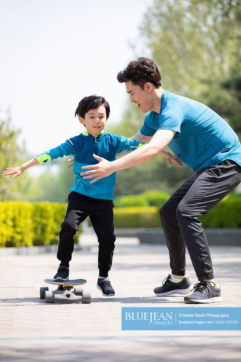 Chinese father teaching his son to skateboard