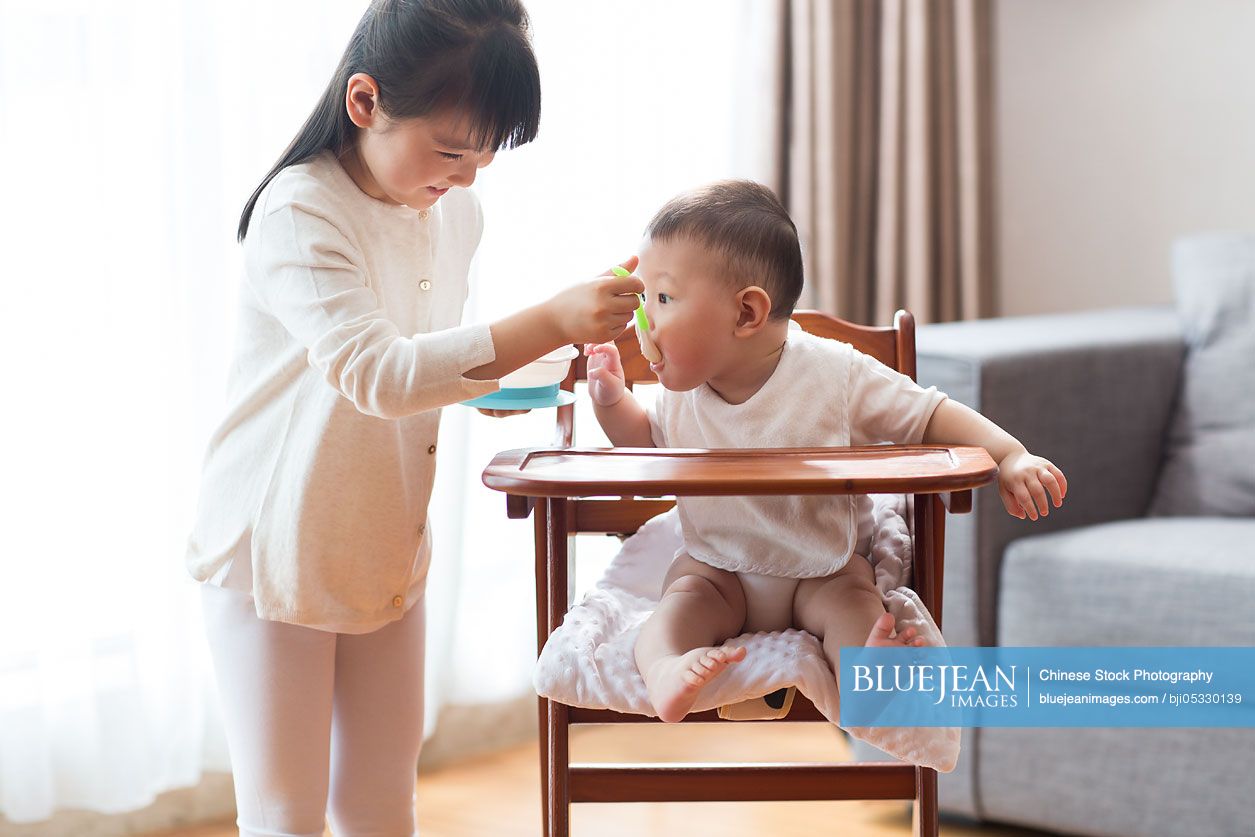 Little Chinese girl feeding baby