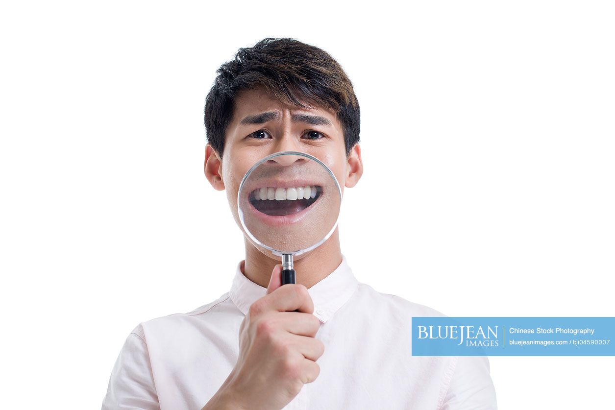 Young Chinese man holding a magnifying glass in front of his mouth