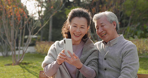 Cheerful senior Chinese couple using smart phone in the park,4K