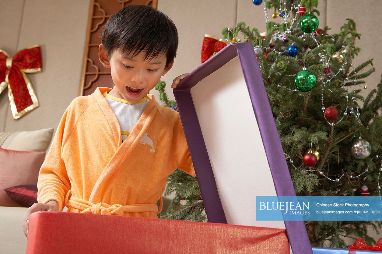 Young Chinese boy excitedly opening Christmas presents