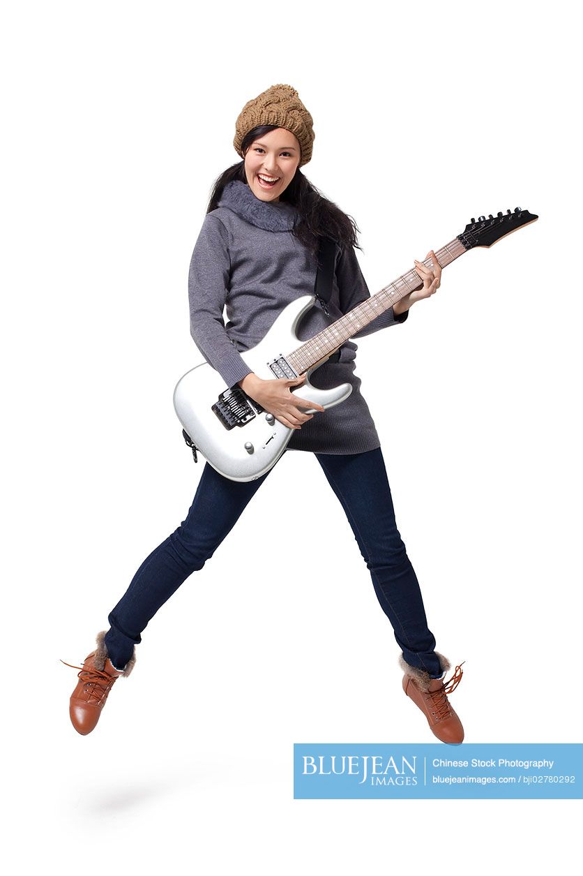 Stylish young Chinese woman playing guitar