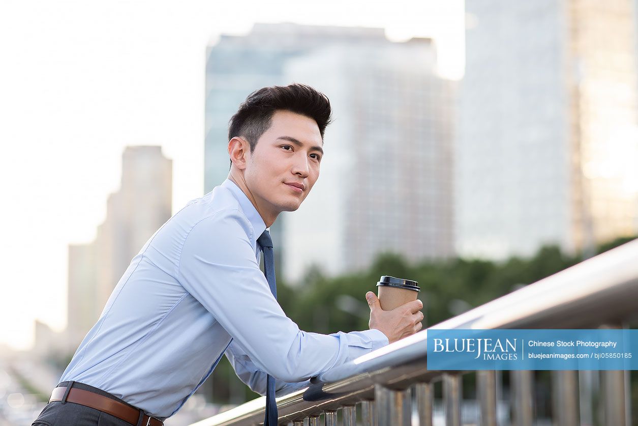 Young Chinese businessman holding a cup of coffee