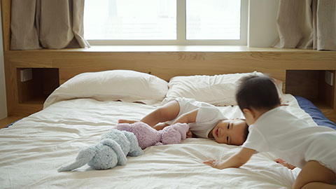 Two twin babies playing on the bed